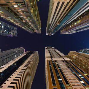 Dramatic low-angle shot of Dubai skyscrapers at night under a clear starry sky.
